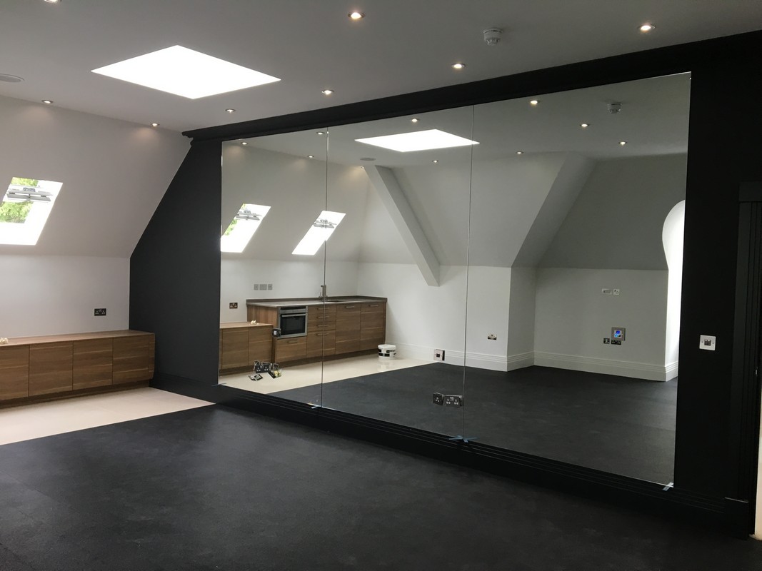 Frameless glass wall dividing loft conversion in East Molesey